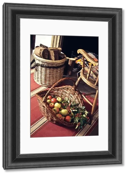 Big decorative basket of Coxs apples with sprays of ornamental berries by open fireplace