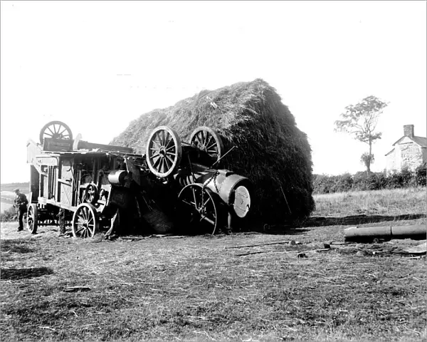 Threshing machine in collision with a hayrick. Possibly in St Stephen in Brannel, Cornwall. Around 1912