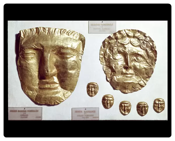 Large gold leaf masks on the face of woman and man and group of five small gold masks