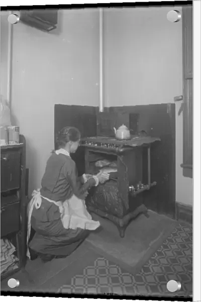 Miss Bates taking bread from the oven, c. 1913 (b  /  w photo)