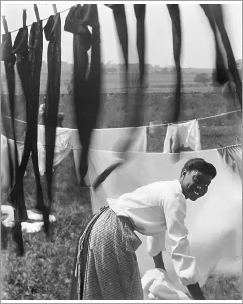 An young African American woman hanging laundry to dry in Newport, Rhode Island, c