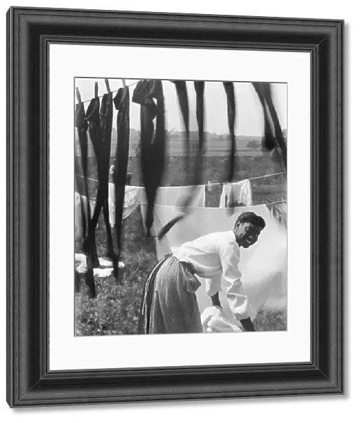 An young African American woman hanging laundry to dry in Newport, Rhode Island, c
