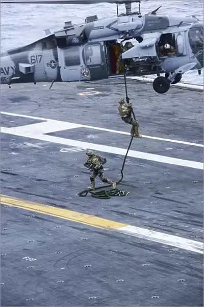 Members conduct a fast roping exercise on the flight deck of USS Carl Vinson