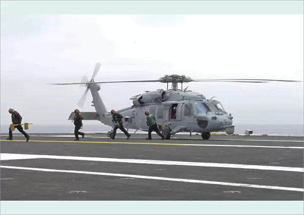 Sailors leave the landing area of an HH-60H Sea Hawk helicopter