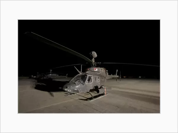 An OH-58D Kiowa sits on its pad at night