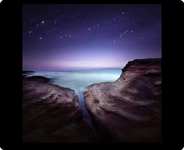Two large rocks in a sea, against starry sky