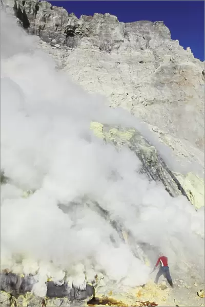 Miner breaking up sulphur deposits at Kawah Ijen Volcano, Java, Indonesia