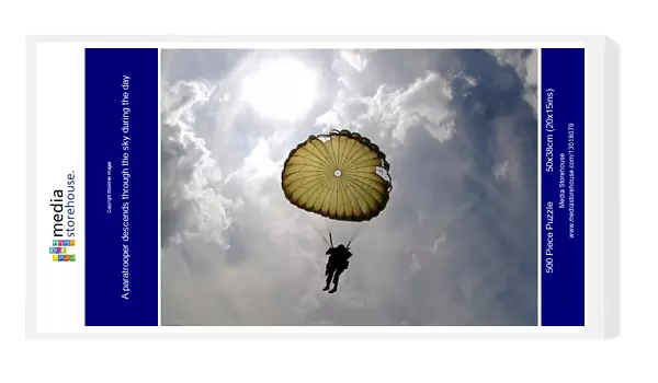 A paratrooper descends through the sky during the day