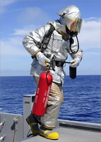 Firefighter carries a CO2 fire extinguisher onto the flight deck of USS Denver