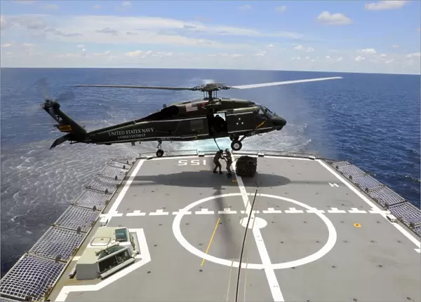 An SH-60F Sea Hawk helicopter lowers pallets onto HMAS Ballarat