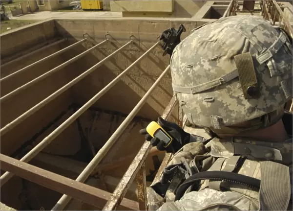 U. S. Army soldier takes a GPS grid reading at a water treatment plant