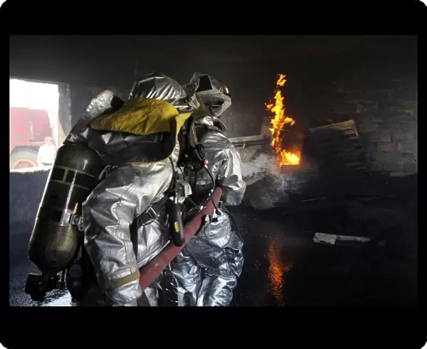 Firefighters extinguish a fire in a training room during live burn training