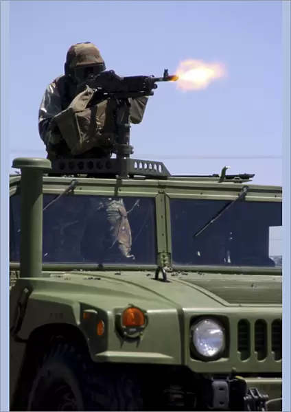 Soldier shoots a M-240B machine gun atop a humvee