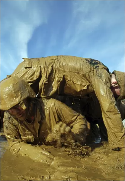 A midshipman crawls through fellow plebes in an obstacle course