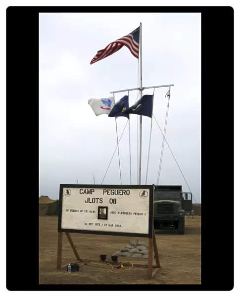 Camp Peguero sign and central flag pole for the Navy, Army and Marine forces camp site