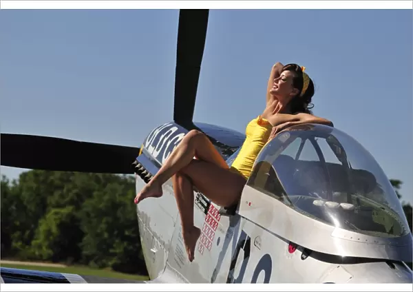 Retro pin-up girl sitting outside the cockpit of a P-51 Mustang