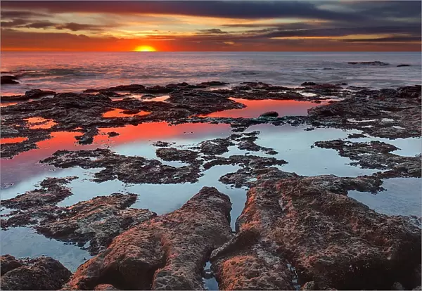 Tidal pools reflect the sunrise colors during the autumn equinox