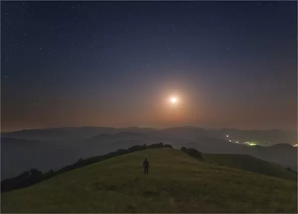 A lone man stands on the mountains at night under the moon, Sudak, Crimea