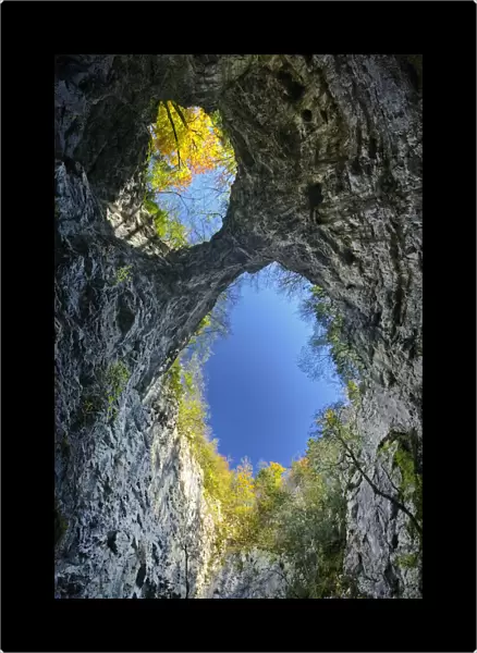 Looking up at the sky through the twin openings in a collapsed cave ceiling, Zelske Jame
