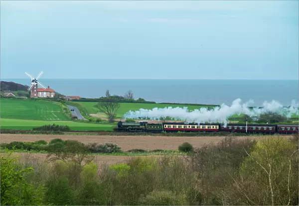 Steam train on the Heritage Poppy Line from Sheringham to Holt, with Weybourne Mill in background