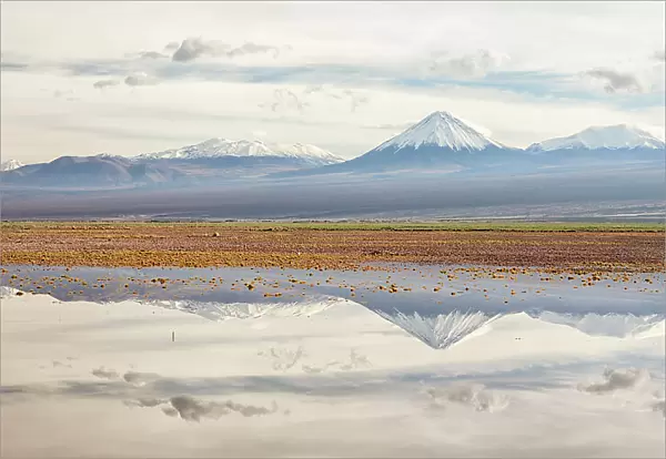 Licancabur volcano and surrounding mountains reflected in waters of a severe flood caused by climate change. Los Flamencos National Reserve, Antofagasta, Chile. February 2019