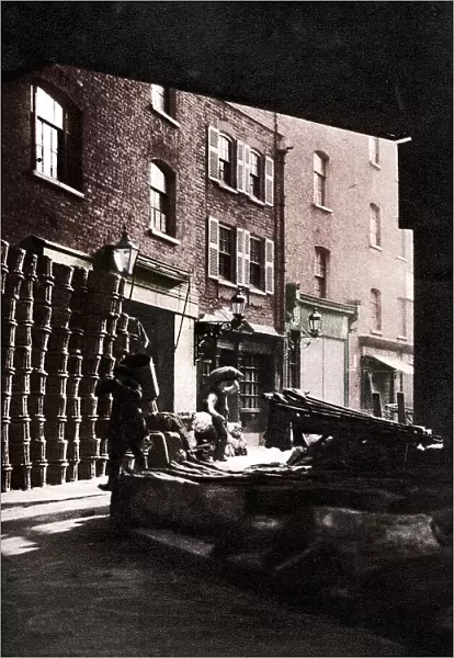 Fruit baskets piled against houses at Borough Market, London, 1926-1927. Artist: Whiffin