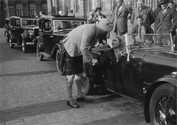 Kitty Brunell in her Aston Martin, chatting to a man in Highland dress, RSAC Scottish Rally, 1933