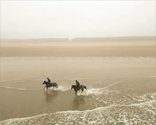 Two horses from the James Owen Racing stables (Newmarket) ride at Holkham beach in Norfolk in a pre-Cheltenham work-out