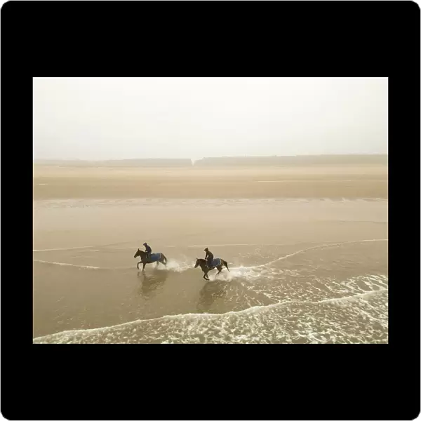 Two horses from the James Owen Racing stables (Newmarket) ride at Holkham beach in Norfolk in a pre-Cheltenham work-out