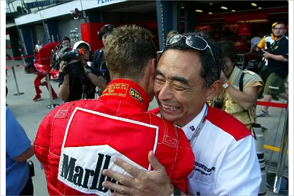 Formula One World Championship: Pole position winner Michael Schumacher Ferrari is embraced by Hiroshi Yasukawa Bridgestone Director of Motorsports
