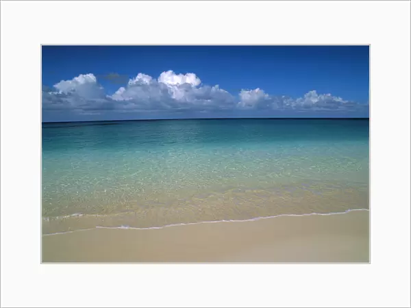 Calm Shoreline Water With Many Different Shades Of Blue, Clouds Above Horizon