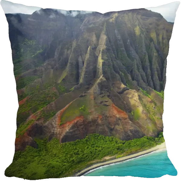 Rugged cliffs and lush foliage with a white sand beach along the coastline of a hawaiian island; Kauai, Hawaii, United States of America