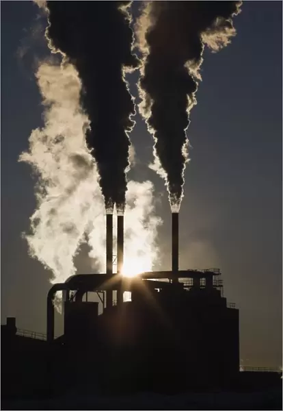 Edson, Alberta, Canada; Silhouette Of Smoke Stacks With Steam And A Sunburst