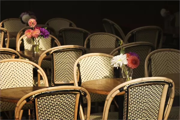 A Bouquet Of Flowers Amongst Empty Parisian Bistro Chairs And Tables; Paris, France