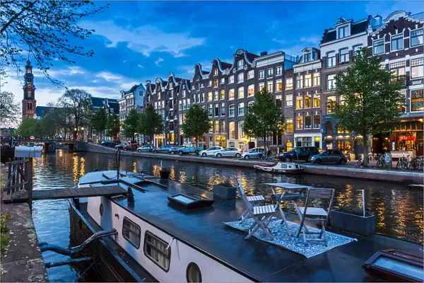 Table and chairs on top of a houseboat moored along the Prinsengracht canal at dusk in Amsterdam, Holland
