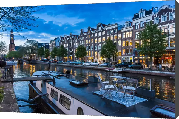 Table and chairs on top of a houseboat moored along the Prinsengracht canal at dusk in Amsterdam, Holland