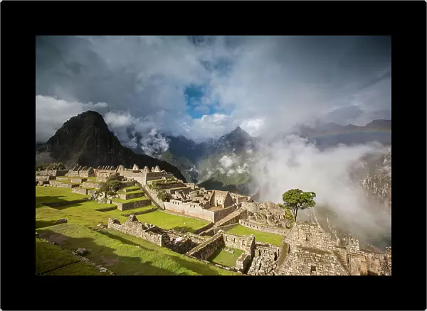 A rainbow emerges from the clouds over Machu Picchu