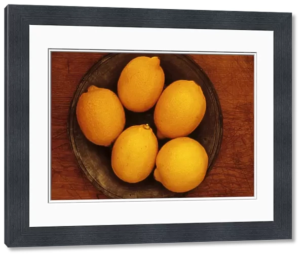 Lemon. Studio shot from above of five lemons on tin or pewter plate on wooden board