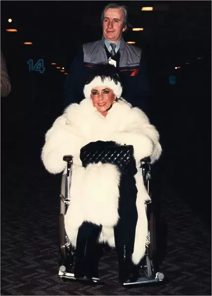 Liz Taylor is pushed through Heathrow airport ijn a wheelchair