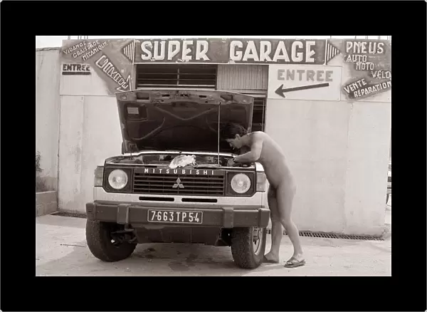 Naturist Nudist Village - July 1987 naked man working on a vehicle in the garage