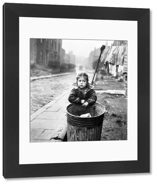 Little girl stands by a dustbin in a Bradford Slum. November 1953 D6539