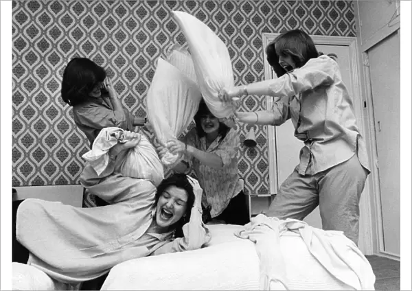 Nolan sisters Maureen flops on the bed under the combined assault of Anne, Left