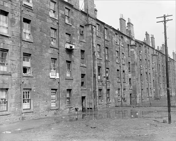 A small boy plays in the squalor outside tenement blocks in Govan, Glasgow