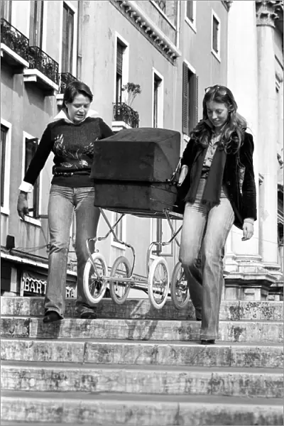 People: Culture: General scenes in Venice. A couple of young women carry a pram over one