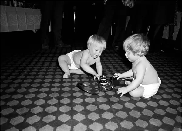 Two young babies seen here examining a camera at a gathering of them parents of a West