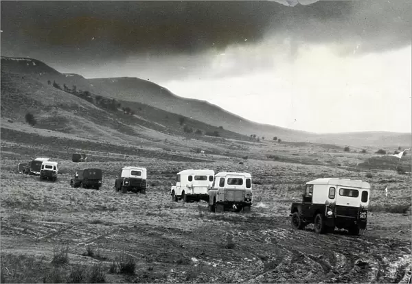 Churning through layers of mud, a line of Land Rovers move cross country towards