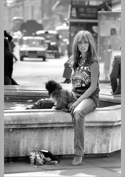Woman stops at a fountain to rest her tired feet after walking her dog around the Kings