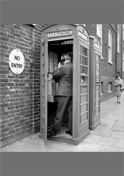 Man using a telephone box. The red telephone box was designed by Sir Giles Gilbert Scott