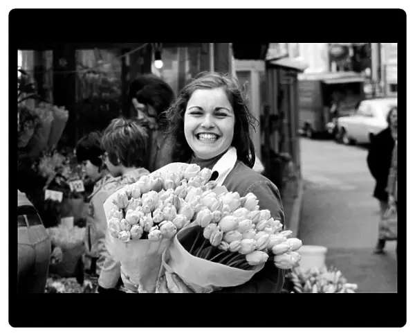 A young girl of Amsterdam holding bunches of tulips during the season May 1975