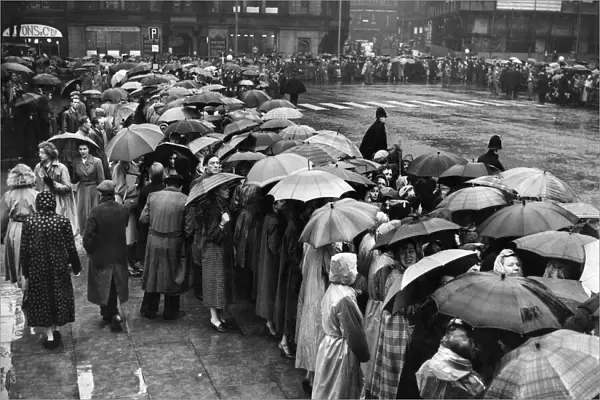 Manchester crowds seek protection from the rain under their umbrellas whilst waiting for